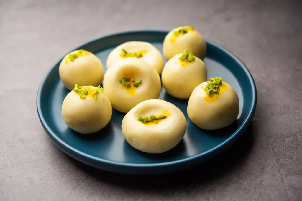Traditional Indian milk peda sweets garnished with pistachios on a blue plate – Satadhar Sweets